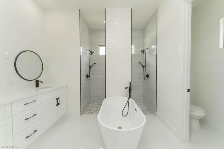 Full bathroom featuring a freestanding bath, tiled shower, vanity, toilet, and tile patterned floors