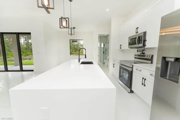 Kitchen featuring stainless steel appliances, a sink, white cabinets, a kitchen island with sink, and recessed lighting
