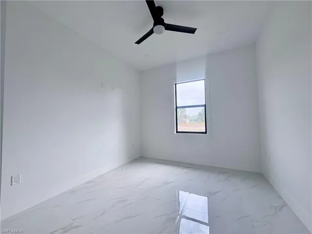 Spare room featuring marble finish floor, ceiling fan, and baseboards