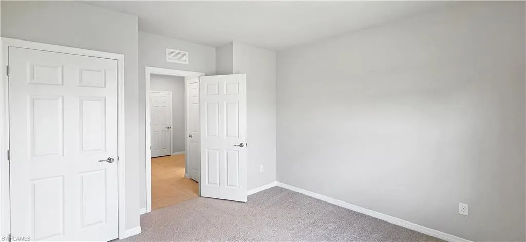 Light gray wall paint with white trim, gray carpet flooring, and white paneled doors
