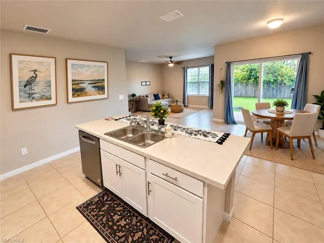 Central kitchen island with an integrated double basin sink, white cabinetry, and light-toned countertop
