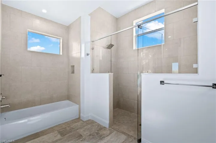 Full bath with walk in shower, a garden tub, and light wood-type flooring