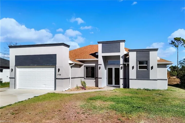 Contemporary house with french doors, stucco siding, a front lawn, and concrete driveway