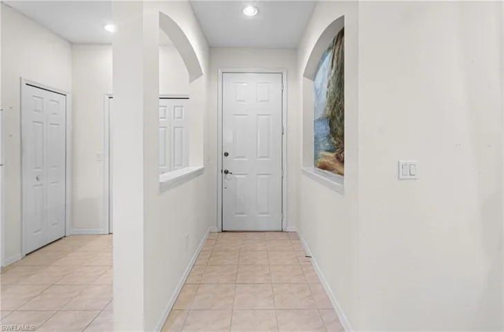 Hallway with light tile patterned floors, arched walkways, and recessed lighting