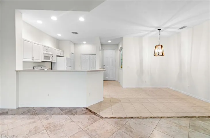 Kitchen with white cabinets, light countertops, recessed lighting, white appliances, and a peninsula