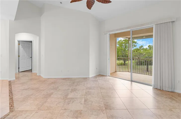 Spare room featuring ceiling fan, high vaulted ceiling, light tile patterned floors, and arched walkways