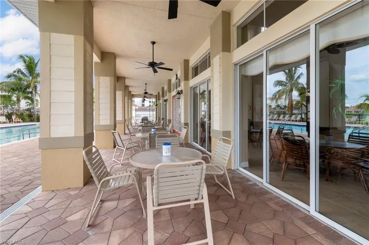View of patio with outdoor dining space, ceiling fan, and a community pool