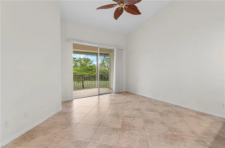 Spare room featuring a ceiling fan, lofted ceiling, and light tile patterned floors