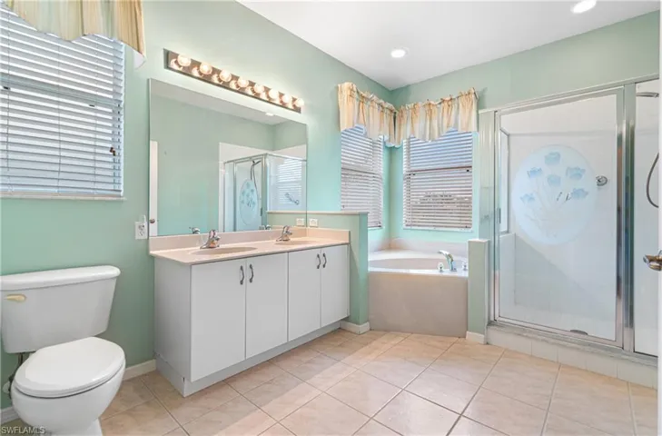 Full bathroom with double vanity, a shower stall, a bath, and light tile patterned floors