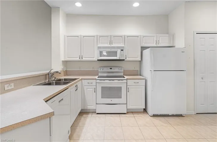 Kitchen featuring white appliances, light countertops, white cabinetry, recessed lighting, and light tile patterned floors