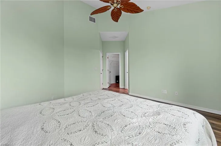 Unfurnished bedroom with a ceiling fan, a high ceiling, and dark wood-type flooring