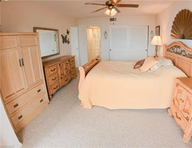 Bedroom with ceiling fan, a closet, and light carpet