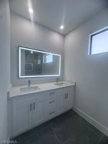 Bathroom with double vanity, tile patterned floors, and baseboards