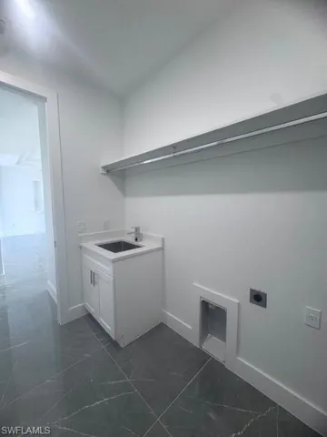 Laundry room featuring hookup for an electric dryer, baseboards, cabinet space, and dark marble finish flooring