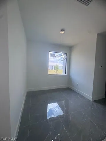 Unfurnished room featuring baseboards and dark marble finish flooring
