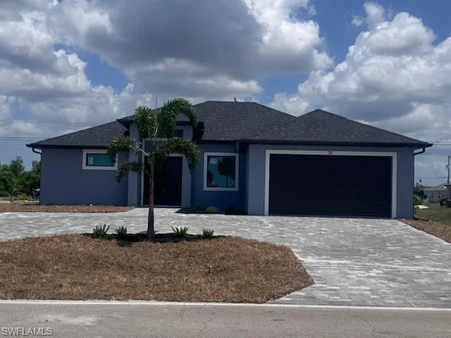 View of front of property with decorative driveway, a garage, and stucco siding
