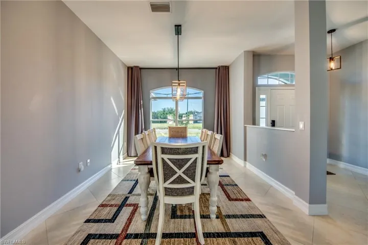 Tiled dining room with a healthy amount of sunlight and a notable chandelier