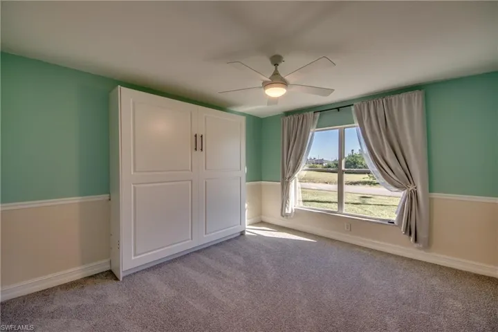 Bedroom featuring Murphy Bed, ceiling fan and light colored carpet