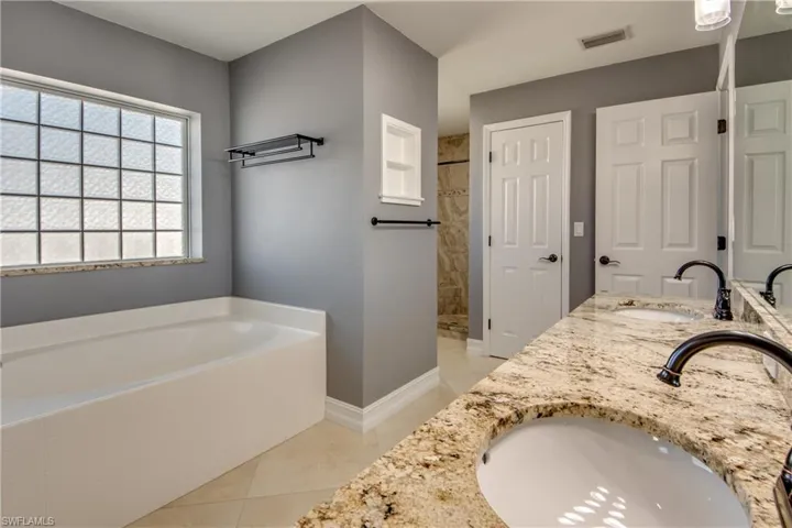 Primary bathroom with tile patterned flooring, vanity, and shower with separate bathtub