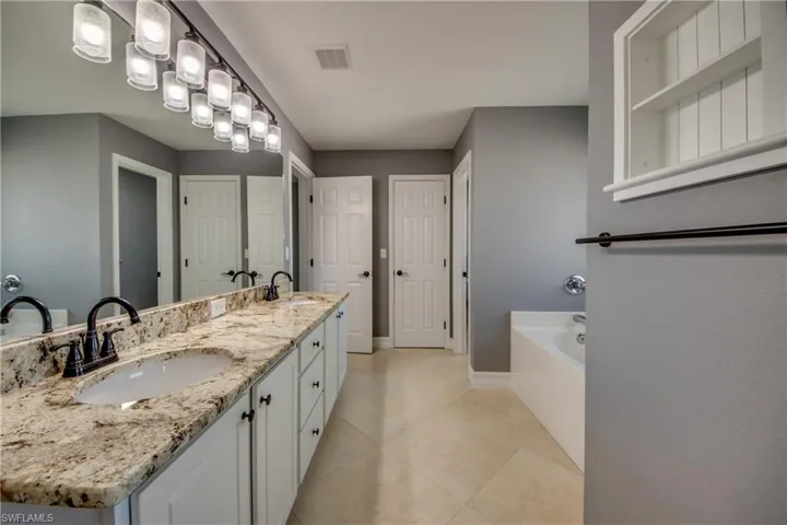 Primary bathroom featuring tile patterned floors, a washtub, and vanity