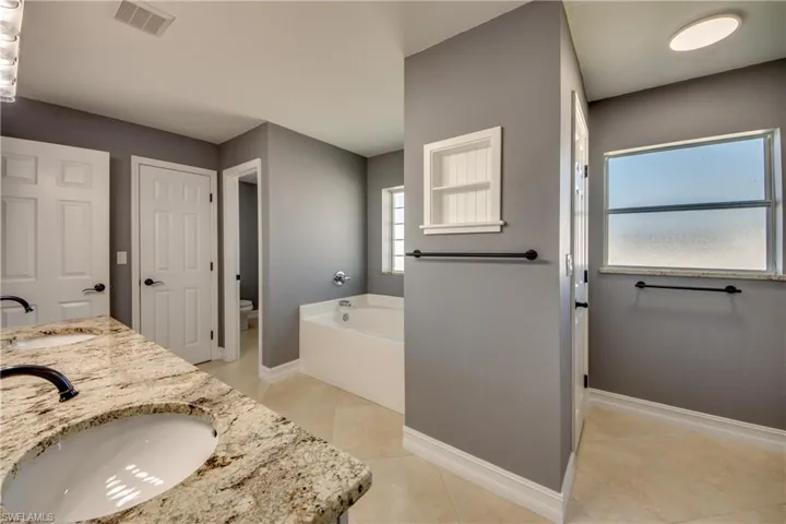 Primary bathroom with a tub to relax in, separate shower, tile patterned flooring, vanity, and toilet