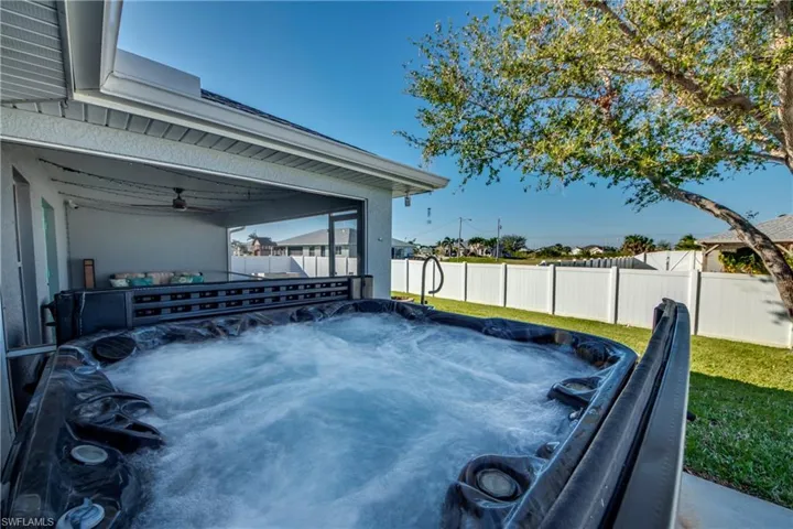 View of patio with ceiling fan and a hot tub