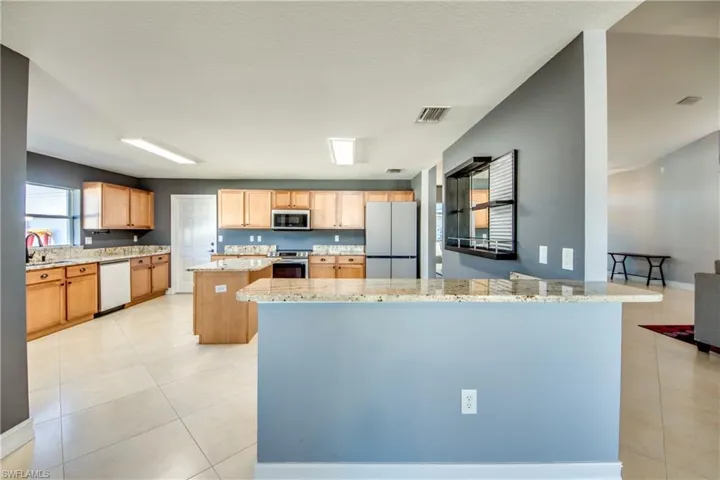 Kitchen with a center island, sink, light stone counters, kitchen peninsula, and stainless steel appliances