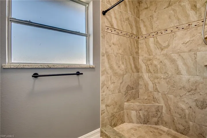 Primary bathroom featuring a healthy amount of sunlight and tiled shower