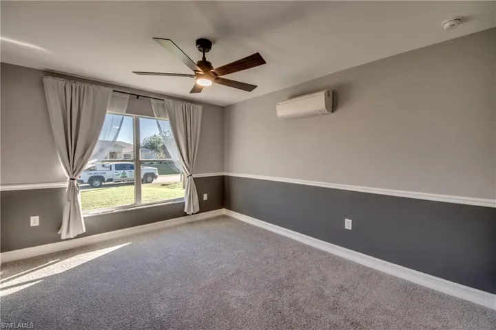 Carpeted spare room with an AC wall unit and ceiling fan