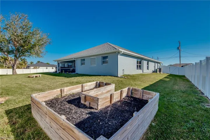 Back of property featuring a yard and a raised bed garden