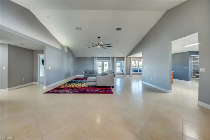 Living room featuring light tile patterned floors, high vaulted ceiling, and ceiling fan