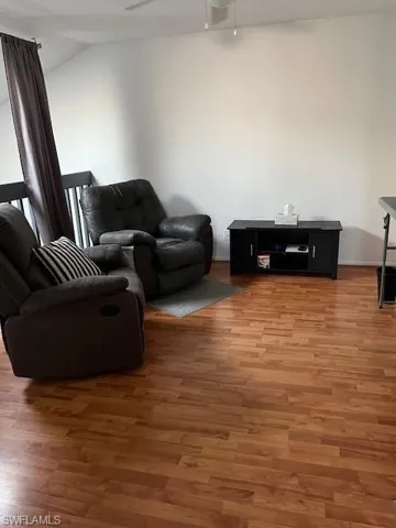 Living room featuring lofted ceiling, dark hardwood / wood-style floors, and ceiling fan