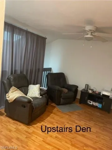 Living room featuring hardwood / wood-style flooring, lofted ceiling, and ceiling fan