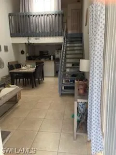 Living room with light tile patterned floors and a high ceiling