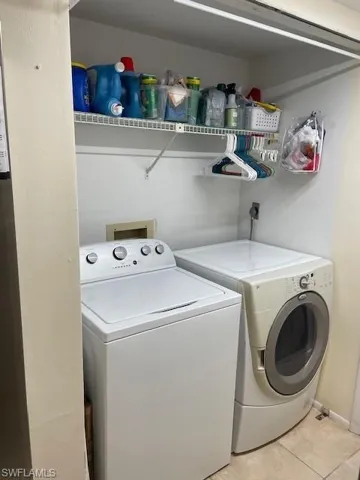 Washroom featuring light tile patterned flooring and washing machine and clothes dryer