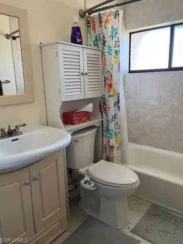 Full bathroom with vanity, shower / tub combo, toilet, and tile patterned floors