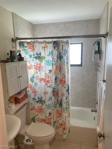 Full bathroom featuring tile patterned flooring, shower / bathtub combination with curtain, toilet, and sink