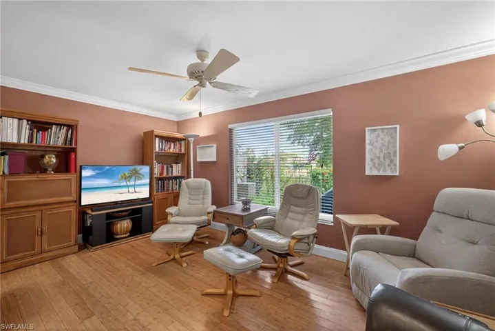 Living area with light wood-style flooring, ornamental molding, and a ceiling fan