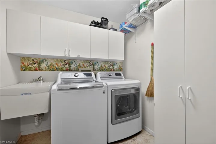 Washroom with cabinet space, washer and dryer, and light tile patterned floors