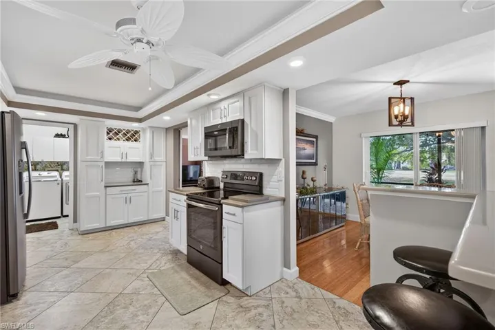 Kitchen featuring appliances with stainless steel finishes, white cabinets, crown molding, decorative backsplash, and separate washer and dryer