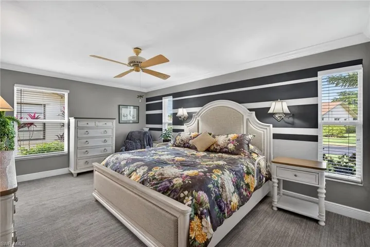 Bedroom featuring an accent wall, ceiling fan, carpet floors, and ornamental molding