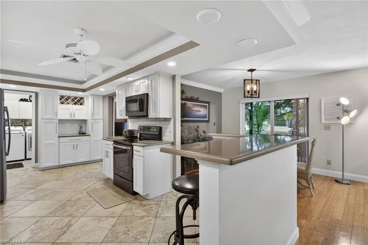Kitchen featuring electric range oven, ornamental molding, dark countertops, a breakfast bar, and tasteful backsplash