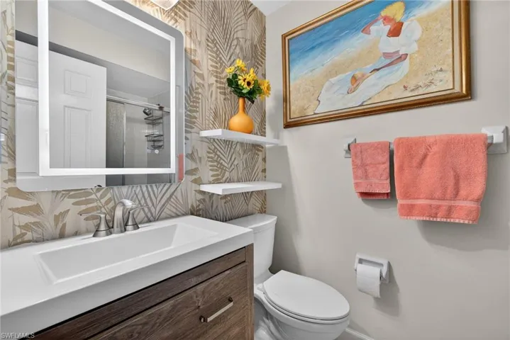 Full bath featuring a stall shower, vanity, tasteful backsplash, and wallpapered walls