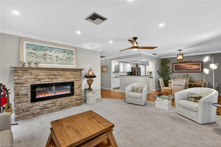 Living room with recessed lighting, ornamental molding, a fireplace, and ceiling fan