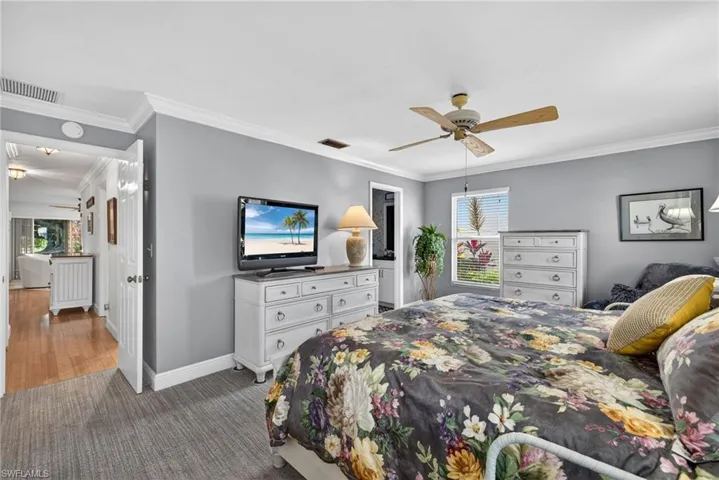Carpeted bedroom with ornamental molding, a closet, and a ceiling fan