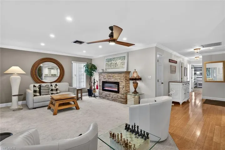 Living room with a fireplace, ornamental molding, a ceiling fan, and recessed lighting