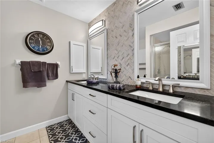 Bathroom with a stall shower, light tile patterned floors, and double vanity