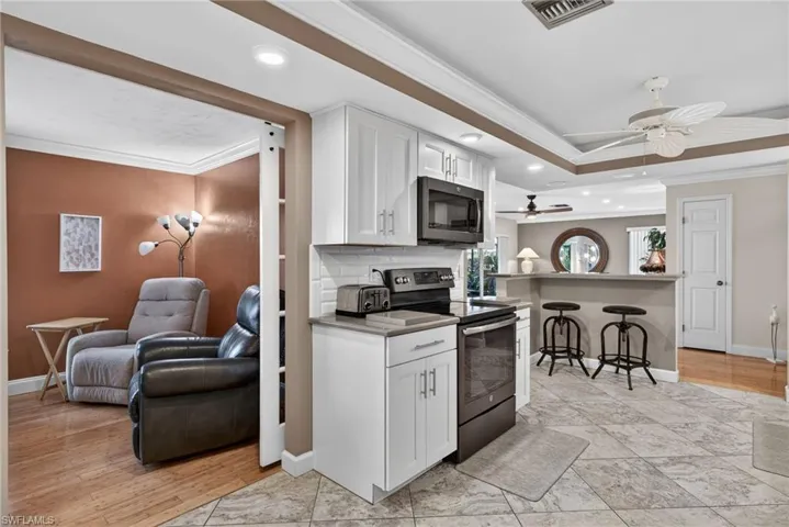 Kitchen with crown molding, a breakfast bar, open floor plan, appliances with stainless steel finishes, and white cabinetry