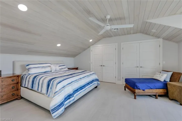 Bedroom with lofted ceiling, wooden ceiling, two closets, ceiling fan, and wood finished floors