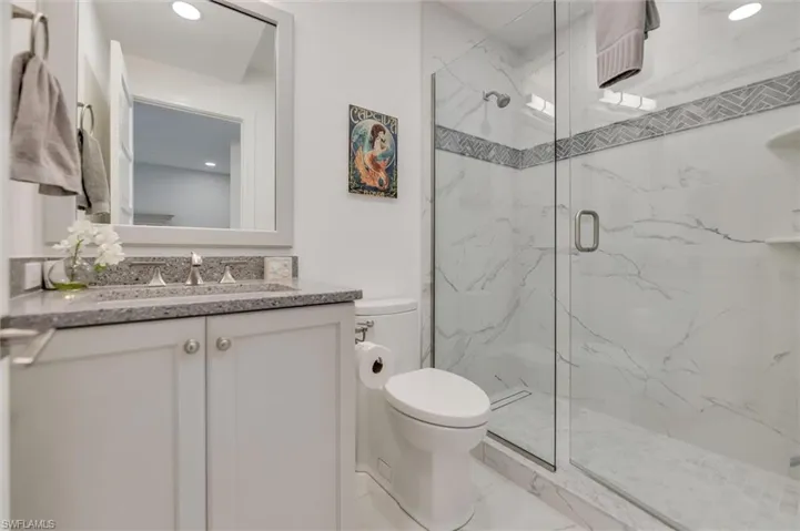 Full bath with a marble finish shower, vanity, and recessed lighting